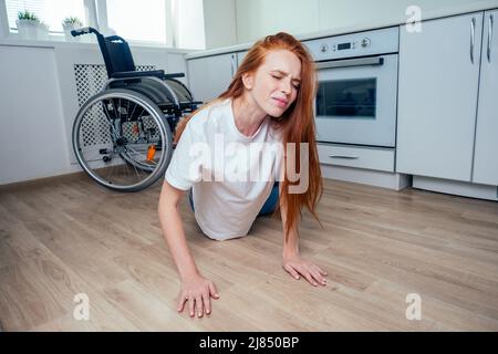 Rothaarige Ingwerfrau, die im Küchenzimmer herunterfiel und um Hilfe kriecht Stockfoto