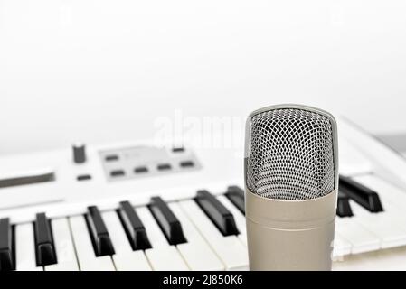 Professionelles Studiomikrofon für sprach- und Musikaufnahmen vor unscharfem Synthesizer-Keyboard-Hintergrund mit Kopierraum. Stockfoto