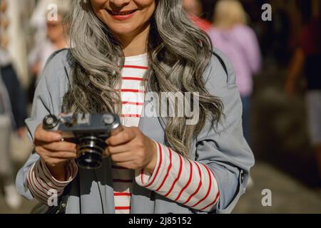 Gut gekleidete Frau beim Durchsuchen von Kamerabildern im Freien Stockfoto