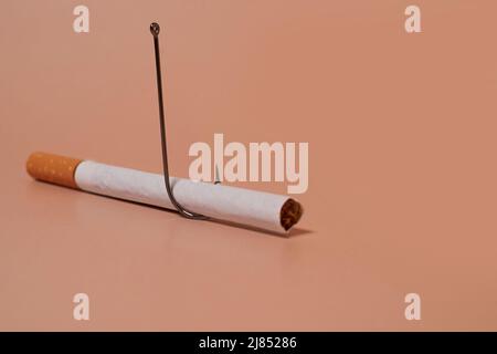 Zigarette mit Fischhaken auf farbigem Hintergrund Stockfoto