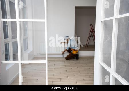 Ein Mann wechselt die Heizung im Haus, Heizkörper. Das Konzept der modernen Heizung, Ersatz der alten durch eine neue. Wärme im Haus Stockfoto