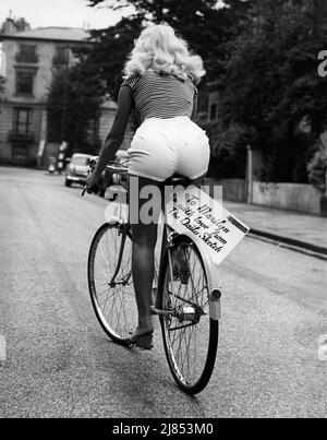 16. Juli 1956, London, England: Eine blonde Frau in Shorts fährt auf einem Fahrrad, das Marilyn Monroe vorgestellt wurde, nachdem sie erwähnt hatte, dass sie Surrey auf einem Fahrrad umfahren wollte. Fahrrad hat ein Schild angebracht und sagt: "An Marilyn mit Liebe aus dem Daily Sketch." (Bild: © Keystone Press Agency/ZUMA Press Wire) Stockfoto