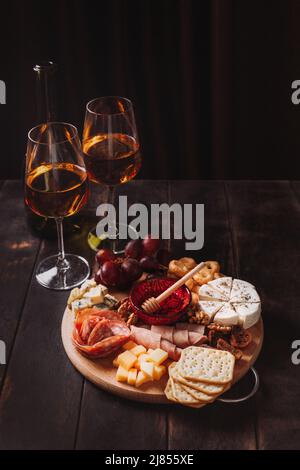 Wurst und Käse, geschnitten mit Obst, Keksen und Sauce, mit zwei Gläsern weißem Portwein und einer Flasche. Aufschnitt und Käseplatte Stockfoto