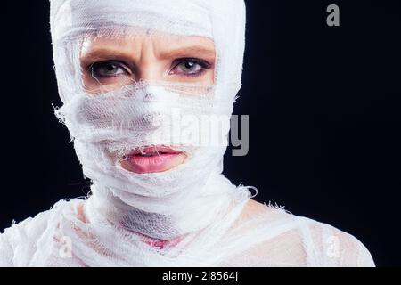 Glamouröse Mama Frau in Verbänden am ganzen Körper in Studio schwarzen Hintergrund. Halloween-Party oder plastische Chirurgie Opfer Konzept Stockfoto