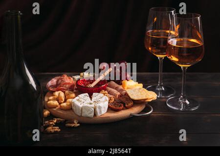 Wurst und Käse, geschnitten mit Obst, Keksen und Sauce, mit zwei Gläsern weißem Portwein und einer Flasche. Aufschnitt und Käseplatte Stockfoto