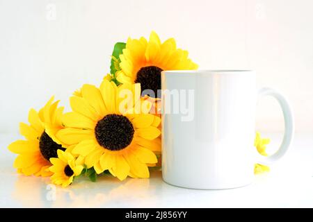 Weißer Kaffeebecher Mockup mit Bouquet von gelben Sonnenblumen, Copyspace. Stockfoto