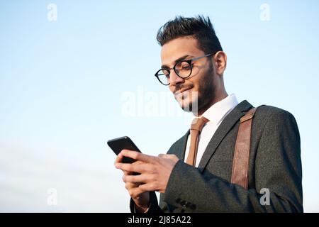 Unten sehen Sie Inhalt jungen arabischen bärtigen Geschäftsmann in Anzug mit Smartphone unterwegs Stockfoto
