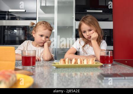 Zwei kleine Mädchen Geschwister haben Spaß und essen in der Küche zu Hause mit japanischer Nahrung. Stockfoto