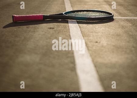 Oberfläche des Tennisschlägers auf weißen Linien auf dem Tennisplatz bei Sonnenuntergang, Platz zum Kopieren Stockfoto