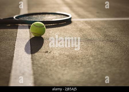 Oberfläche des Tennisballs und Schlägers auf weißen Linien auf dem Tennisplatz bei Sonnenuntergang, Platz kopieren Stockfoto