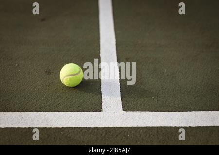 Hohe Winkelansicht des gelben Tennisballs durch weiße Linien auf dem Tennisplatz, Kopierraum Stockfoto