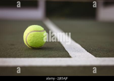 Nahaufnahme des gelben Tennisballs durch weiße Linien auf dem Tennisplatz, Kopierbereich Stockfoto