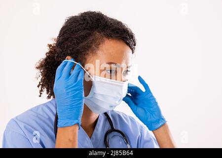 Nahaufnahme einer afroamerikanischen Ärztin mit mittlerem Erwachsenen und Maske vor weißem Hintergrund Stockfoto
