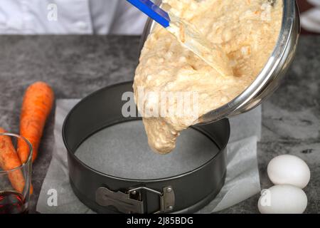 Eine Mischung aus geriebenen Karotten und geschlagenen Proteinen wird in eine Backform gegossen Stockfoto