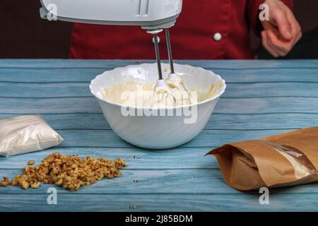 Eiweiß und Granulatzucker mit einem elektrischen Mixer schlagen. Stockfoto