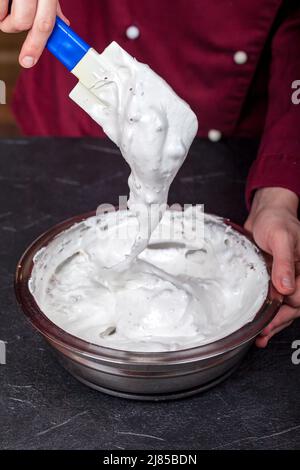 Geschlagenes Eiweiß. Mit zerkleinerten Nüssen vermischen Stockfoto