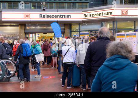 Hamburg, Deutschland. 13.. Mai 2022. Zahlreiche Reisende stehen in einer langen Schlange vor dem DB Travel Center am Hamburger Hauptbahnhof. Aufgrund eines Kabelbrands in Hamburg ist der Fernverkehr stark gestört. Quelle: Jonas Walzberg/dpa/Alamy Live News Stockfoto