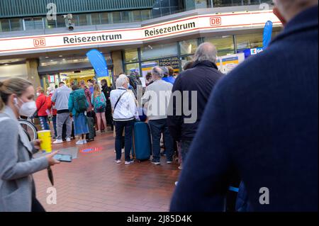 Hamburg, Deutschland. 13.. Mai 2022. Zahlreiche Reisende stehen in einer langen Schlange vor dem DB Travel Center am Hamburger Hauptbahnhof. Aufgrund eines Kabelbrands in Hamburg ist der Fernverkehr stark gestört. Quelle: Jonas Walzberg/dpa/Alamy Live News Stockfoto