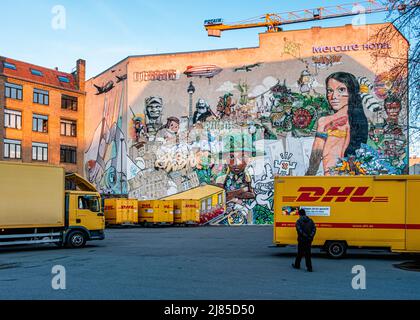 Geparkte Lastwagen des DHL International Courier neben einer mit Graffiti und Street Art bedeckten Wand in Kreuzberg, Berlin. Kurier-, Paket- und Express-Postdepot der Deutschen Post Stockfoto
