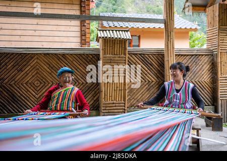 (220513) -- GONGSHAN, 13. Mai 2022 (Xinhua) -- die Dulong-Tochter Li Wenshi (L) und ihre Tochter weben Dulong-Decken im Dorf Dizhengdang der Gemeinde Dulongjiang, dem Autonomen Kreis Gongshan Dulong und Nu, südwestlich der Provinz Yunnan, 10. Mai 2022. Dulong ist eine in den Bergen lebende ethnische Gruppe im Südwesten Chinas. Es ist eine der am wenigsten bevölkerten Nationalitäten der chinesischen Minderheit. 2018 schüttelte die ethnische Gruppe Dulong die Armut als Ganzes ab, ein phänomenaler Durchbruch. Li Wenshi, der die Weben von Dulong-Decken von ihrer Mutter erbte, hat ihre Expertise genutzt, um verschiedene Produkte zu kreieren, die eine sind Stockfoto