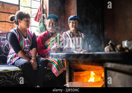 (220513) -- GONGSHAN, 13. Mai 2022 (Xinhua) -- Li Wenshi, die Dulong wohnt, und ihre Familienmitglieder unterhalten sich zu Hause im Dorf Dizhengdang der Gemeinde Dulongjiang, dem Autonomen Kreis Gongshan Dulong und Nu, südwestlich der Provinz Yunnan, 10. Mai 2022. Dulong ist eine in den Bergen lebende ethnische Gruppe im Südwesten Chinas. Es ist eine der am wenigsten bevölkerten Nationalitäten der chinesischen Minderheit. 2018 schüttelte die ethnische Gruppe Dulong die Armut als Ganzes ab, ein phänomenaler Durchbruch. Li Wenshi, der die Weben von Dulong-Decken von ihrer Mutter erbte, hat ihre Expertise genutzt, um verschiedene Produkte zu entwickeln, die es sind Stockfoto