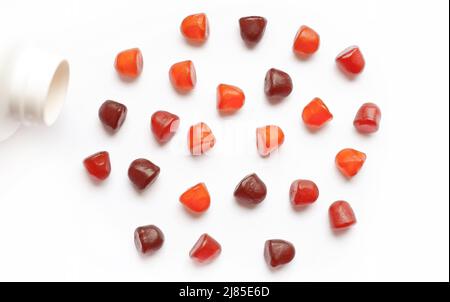 Gruppe von roten, orangen und violetten Multivitamin-Gummibeinen mit der Flasche isoliert auf weißem Hintergrund. Stockfoto