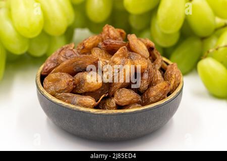 Getrocknete Rosinen auf weißem Hintergrund. Rohe Trauben und Rosinen. Gesunde und frische Nüsse. Nahaufnahme. Lokaler Name besni uzum Stockfoto