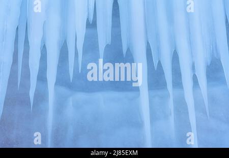 Blaues Eis und Eiszapfen auf den Felsen der Insel Ogoy, Baikalsee, Sibirien, Russland. Abstrakt Winter Natur Hintergrund. Stockfoto