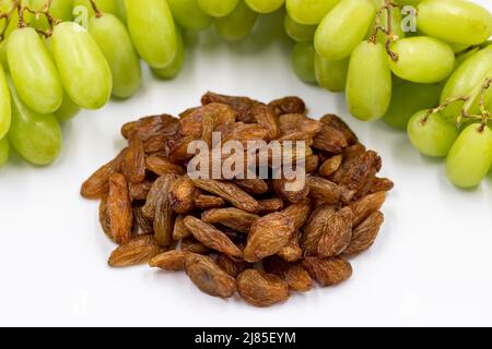 Getrocknete Rosinen auf weißem Hintergrund. Rohe Trauben und Rosinen. Gesunde und frische Nüsse. Nahaufnahme. Lokaler Name besni uzum Stockfoto