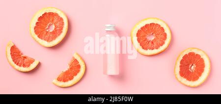 Vitamin C-Flasche mit Zitruslotion und Grapefruitscheiben auf rosa Hintergrund. SPA-Körperbehandlung Konzept. Stockfoto