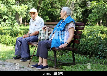 Ein älteres Paar sitzt auf einer Bank im Sommerpark. Alter Mann und Frau zusammen, Freizeit in der Natur, Leben im Ruhestand Stockfoto
