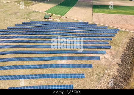 Solarfarm Luftaufnahme, Reihen von PV-Modulen bei einem kleinen Haus Stockfoto