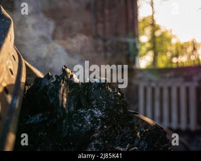 Charkiw Region, Charkow, Skovorodinovka, Skovorodinivka, Ukraine - 05.07.2022: Brennendes Schwelbrand rauchendes Stück Holzfragmente zerstört bauen Stockfoto