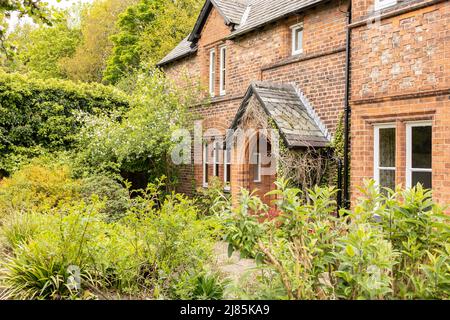 Traditionelles englisches Land umgeben von Bäumen und Sträuchern Cottage Stockfoto