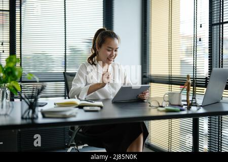 Junge asiatische Geschäftsfrau, die im Büro an einem Laptop arbeitet Stockfoto