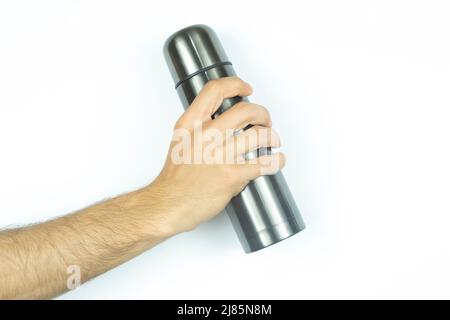 Hand hält eine schwarze Thermosflasche, isoliert auf weißem Hintergrund, Vorderansicht einer Wasserflasche, trinkt ein heißes Getränk mit Thermosflasche Stockfoto