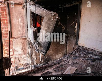 Charkiw, Charkow, Ukraine - 05.07.2022: Innenansicht zerstörtes Fenster der zivilen Wohnung auf dem Feld mit grünem Gras gebrochene Betonwand im Haus rus Stockfoto