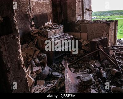 Charkiw, Charkow, Ukraine - 05.07.2022: Blick aus dem zerstörten Wohnküche gebrochener Ofen nach Raketenangriff zersplittert Metallziegel zerbrochener Wal Stockfoto
