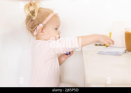 Cochlea-Implantat für Babys. Taubes Kind mit Hörgerät zu Hause Stockfoto