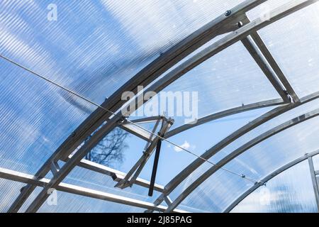 Moderne Gewächshausstruktur. Doppelt gewölbter Stahlrahmen und Polycarbonat-Dach mit automatischem Fenster zum Öffnen Stockfoto