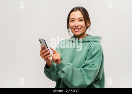 Freundliche Dame, die Videoanruf auf Mobiltelefon oder Rundfunk macht, mit Gadget für die Online-Kommunikation. Innenaufnahme des Studios isoliert auf weißem Hintergrund Stockfoto