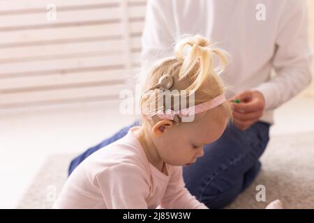 Cochlea-Implantat für Babys. Taubes Kind mit Hörgerät zu Hause Stockfoto