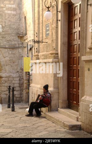 Mann spielt Akkordeon vor einer Kirche einer italienischen Stadt Stockfoto