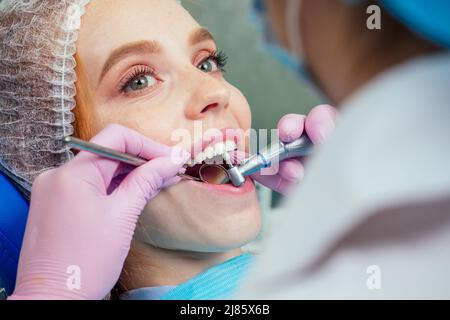 Wunderschöne rothaarige Ingwerfrau sitzt auf dem Zahnstuhl und kam zum Zahnarzt in der Klinik Stockfoto