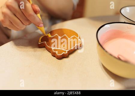 Zubereitung von Lebkuchen. Der Konditor malt Lebkuchen. Meisterkurs über Lebkuchenmalerei. Vorbereitung auf ostern Stockfoto