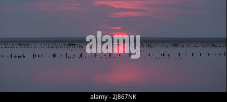 Zauberhafter, verträumter Sonnenuntergang über der Wasseroberfläche des Sees vor dem Hintergrund untergehenden Sonnenlichtes und farbenfroher Wolken Stockfoto