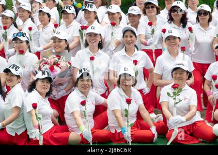 Frauen aus Wenzhou, China, feiern in der Kai Xin Yizhu Tanzgruppe den Muttertag, indem sie für ein Gruppenfoto posieren und Rosen halten. In einem Park in NYC. Stockfoto