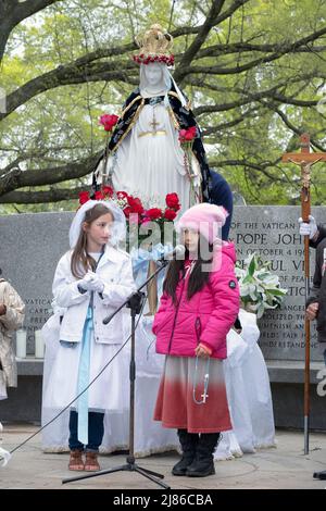 Ein 8-jähriges Mädchen führt in einem Park in Queens, New York City, einen „Maikrönungsgottesdienst“ frommer römischer Katholiken an Stockfoto