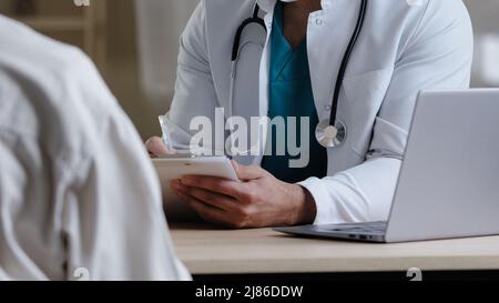 Nahaufnahme männlich unbekannt Arzt Therapeut Mann in weißer medizinischer Uniform sitzen am Schreibtisch konsultieren Patienten Beschwerden geben Rat intern medizinischen Kollegen Stockfoto