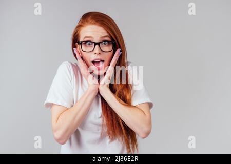 Rothaarige Ingwer-Frau, die sich glücklich fühlt, trägt weißes Baumwoll-T-Shirt im grauen Studio-Hintergrund Stockfoto